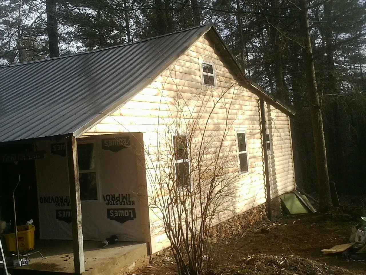 Log siding gable end under a dark metal roof edge in Marlin