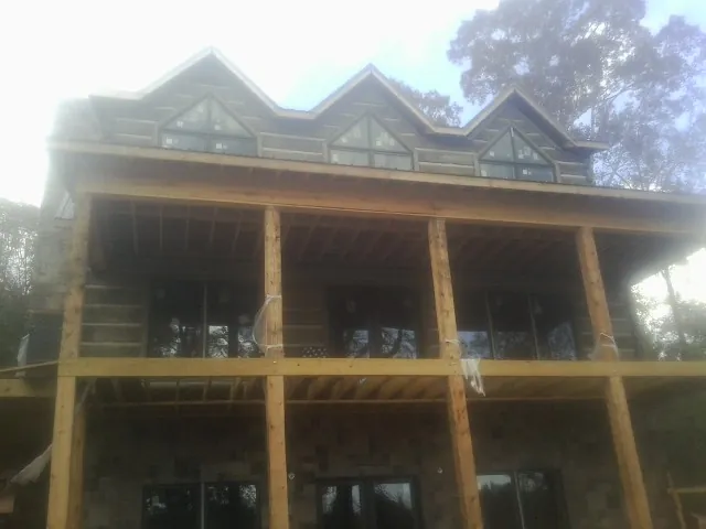 Dormers and porch framing on a large log home under construction — Roof Coating work by our crew in Marlin