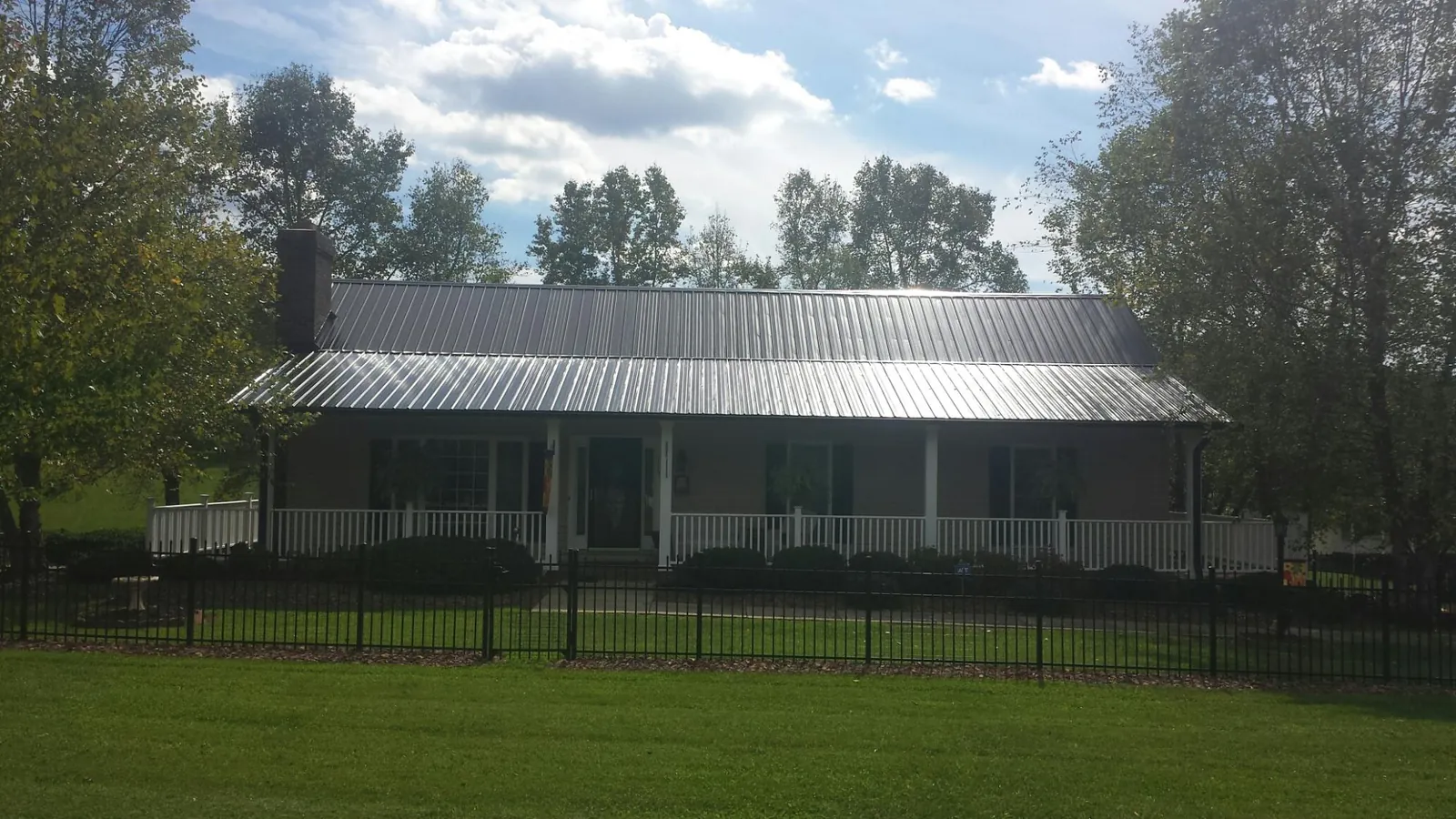 Gray metal roof on a brick ranch with a full width front porch — Gutter Guard Installation work by our crew in Marlin