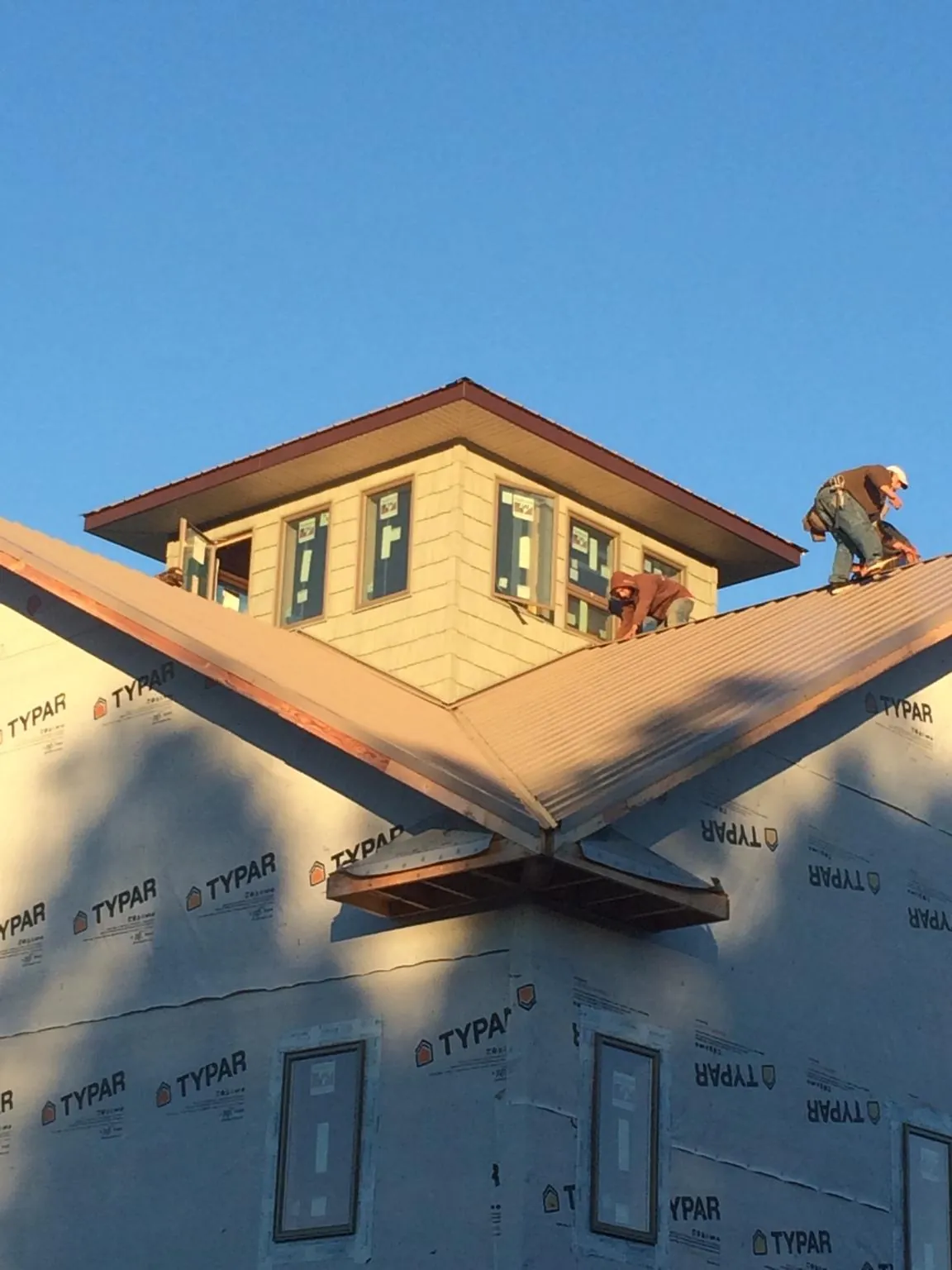 Roofers working around a rooftop cupola on a new metal roof at sunset — Roof Waterproofing in Marlin by Roofing Brothers